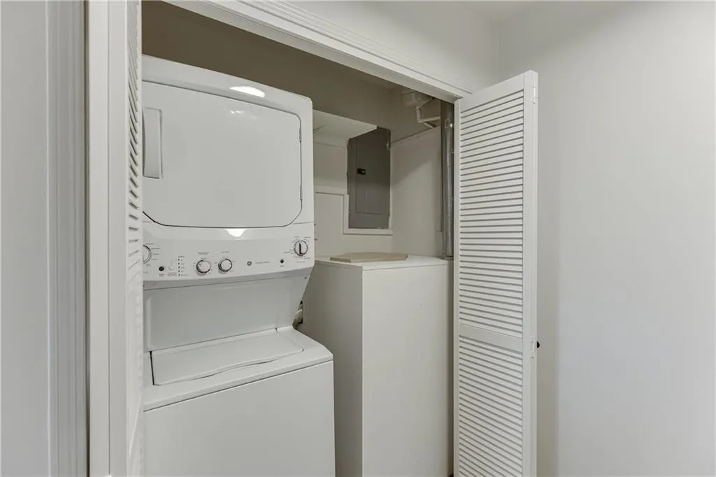 Laundry room featuring stacked washer / dryer, laundry area, and electric panel