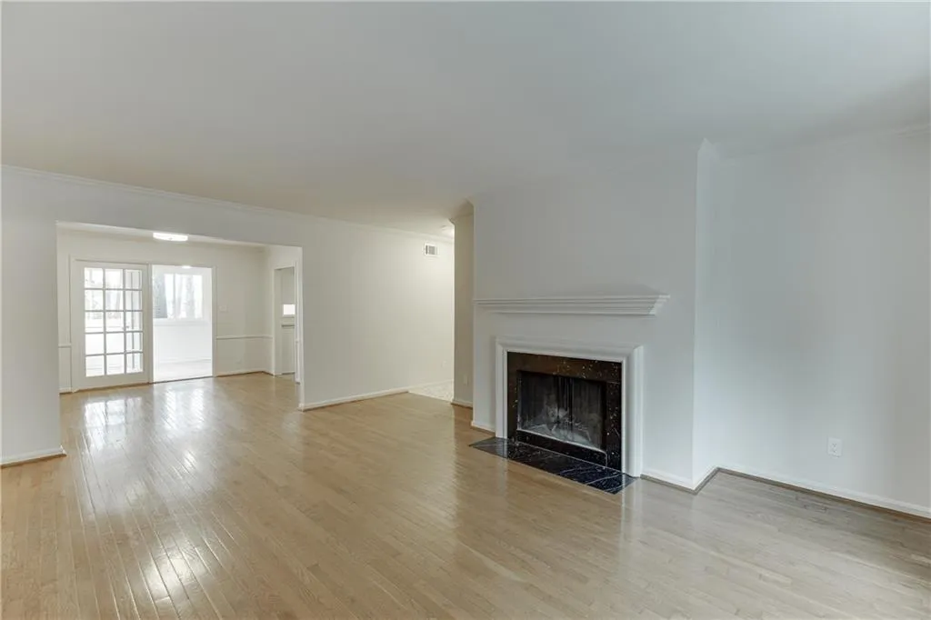 Unfurnished living room featuring light wood-style flooring, ornamental molding, baseboards, and a fireplace