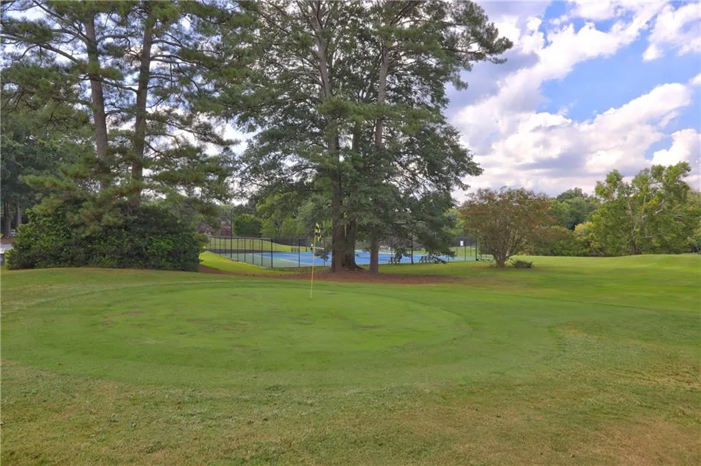 Surrounding community with an area to practice putting, view of golf course, and view of wooded area