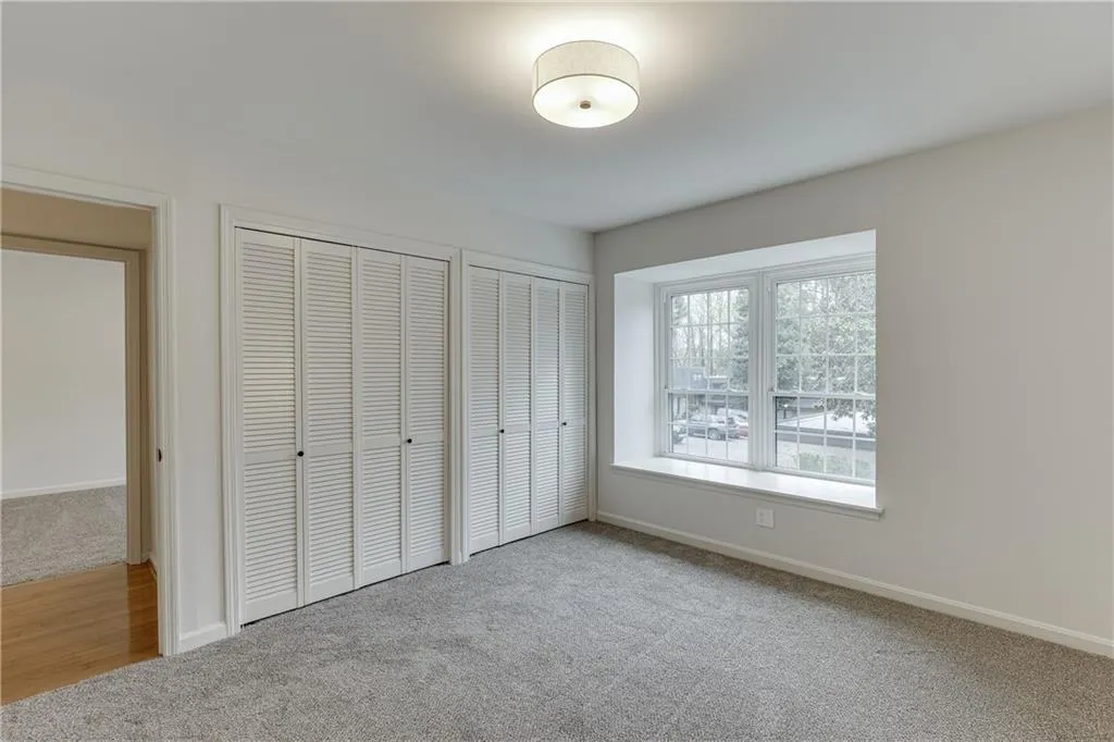 Unfurnished bedroom with carpet flooring, baseboards, and two closets