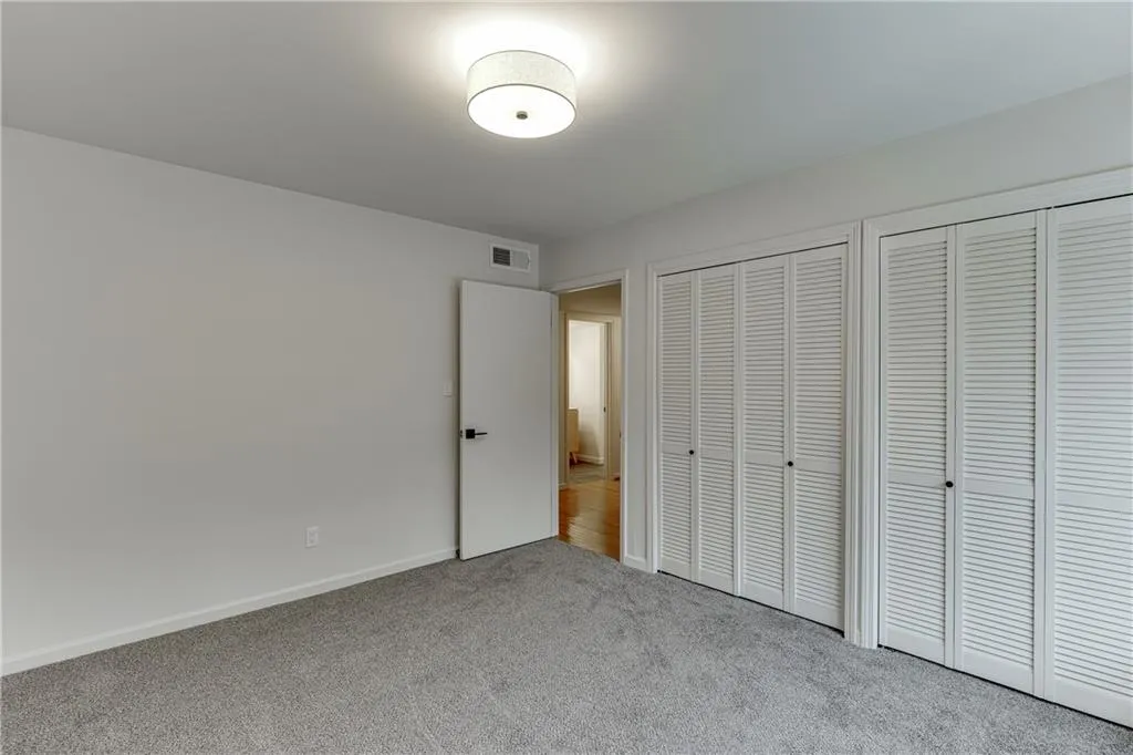 Unfurnished bedroom with baseboards, two closets, visible vents, and carpet