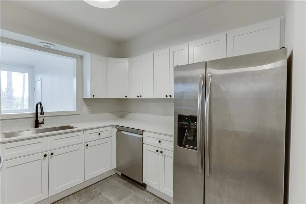 Kitchen with white cabinetry, light countertops, a sink, and appliances with stainless steel finishes