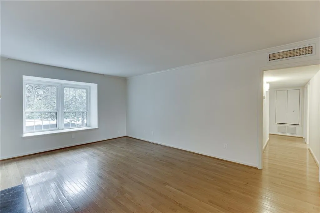 Unfurnished room featuring crown molding, baseboards, light wood finished floors, and visible vents