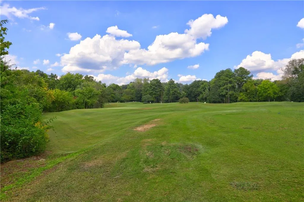 View of home's community with view of golf course and a lawn