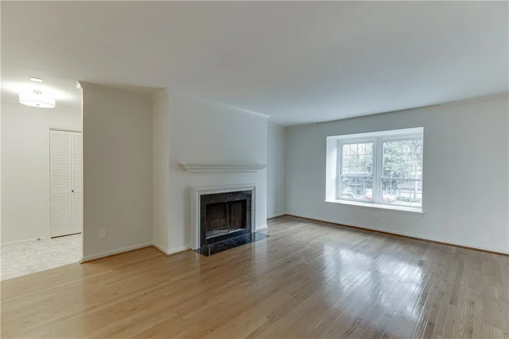 Unfurnished living room featuring ornamental molding, baseboards, a fireplace, and wood finished floors