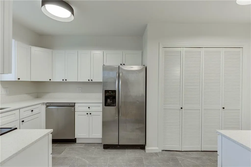 Kitchen with white cabinetry, light stone countertops, and stainless steel appliances