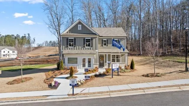 Two-story exterior with board and batten siding, multiple gables, and a prominent front entry with a light fixture