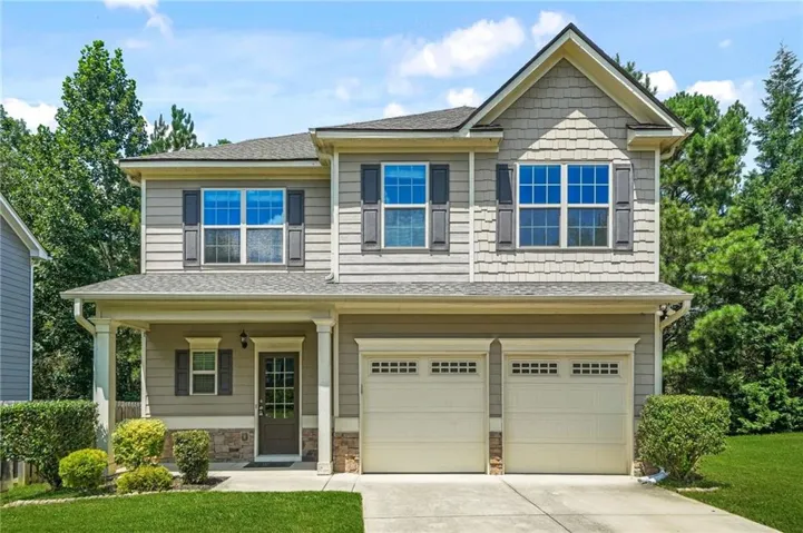 Two-story residence featuring a covered front porch, a two-car garage, and horizontal siding with shake accents