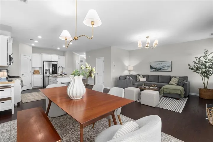 Open-concept living space featuring wood-finish flooring, recessed lighting, and a modern chandelier