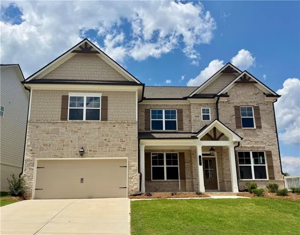 Two-story residence featuring a combination of brick and stone veneer siding, decorative gables with exposed timber accents, and dark window shutters