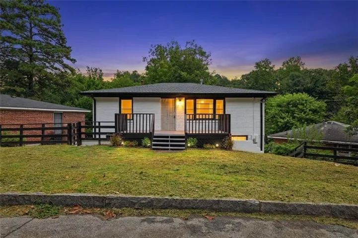 White siding exterior, black trim windows, covered front porch with dark railing, multi-level steps, landscaped front yard