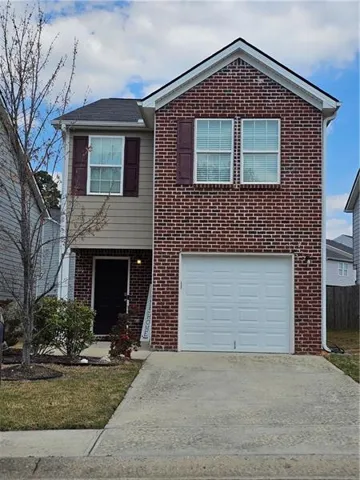View of front of home featuring driveway, brick siding, and an attached garage