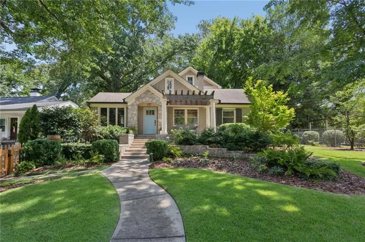Stone and stucco exterior featuring a light blue front door, covered porch with pergola, and a concrete pathway