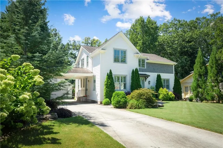 White exterior with gray shake accent siding, featuring a portico entry and a paved driveway