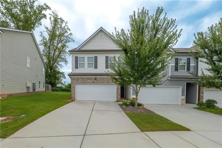 View of front of home with brick siding, an attached garage, and driveway