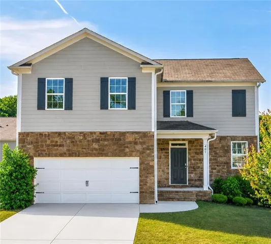 Two-story residence featuring a stone and siding facade, a two-car garage, and a covered entryway