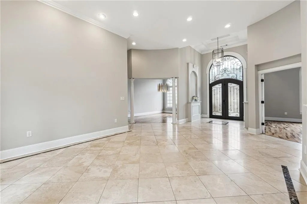 Foyer entrance featuring ornate columns, crown molding, a towering ceiling, and french doors