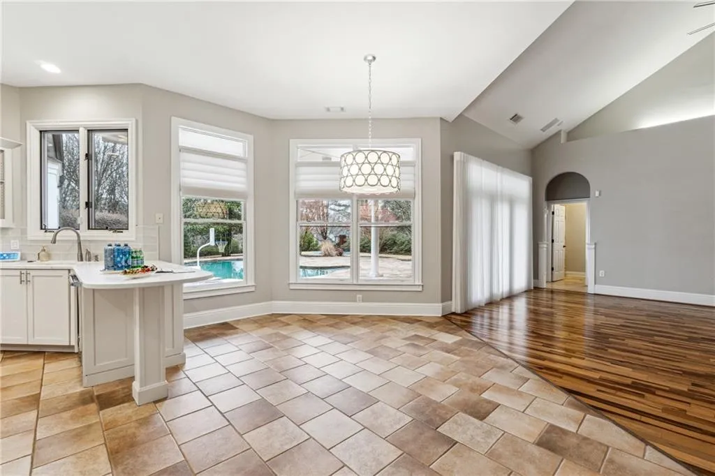 Unfurnished dining area with lofted ceiling, sink, and light tile patterned floors
