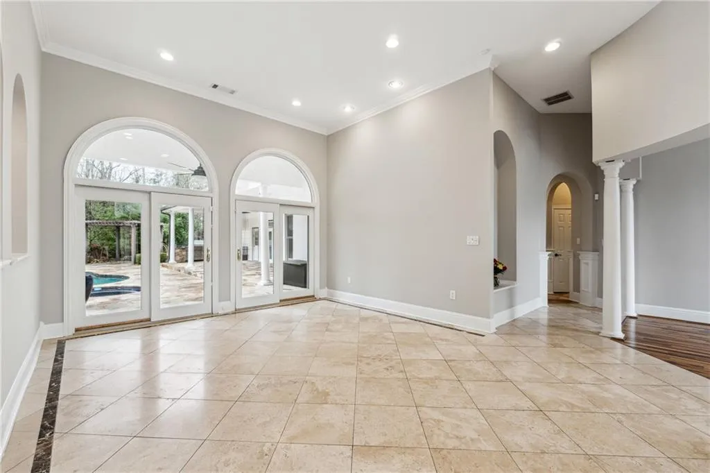 Empty room featuring ornamental molding, decorative columns, and a high ceiling