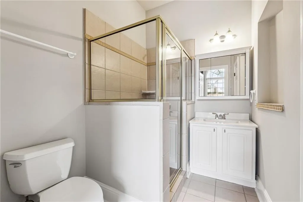 Bathroom featuring vanity, toilet, tile patterned flooring, and a shower with door