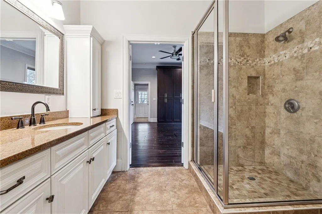 Bathroom with vanity, crown molding, a shower with shower door, and ceiling fan