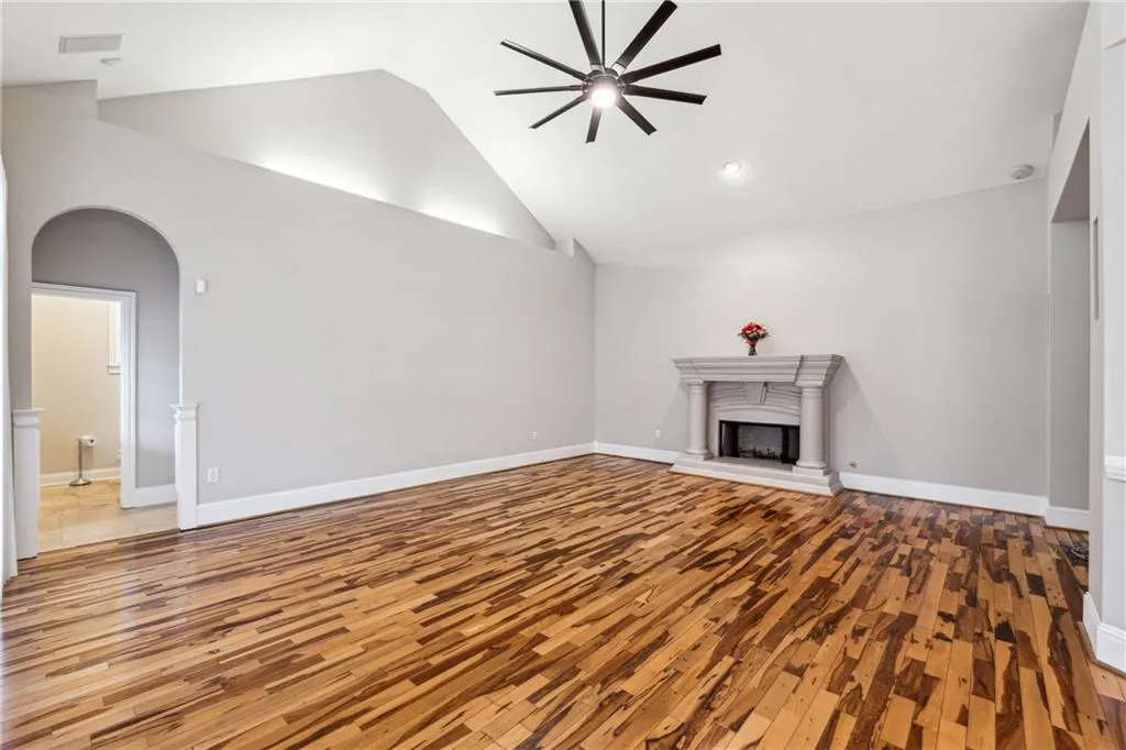 Unfurnished living room featuring high vaulted ceiling, ceiling fan, and light wood-type flooring