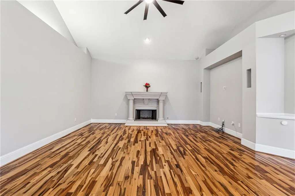 Unfurnished living room with ceiling fan, wood-type flooring, and lofted ceiling