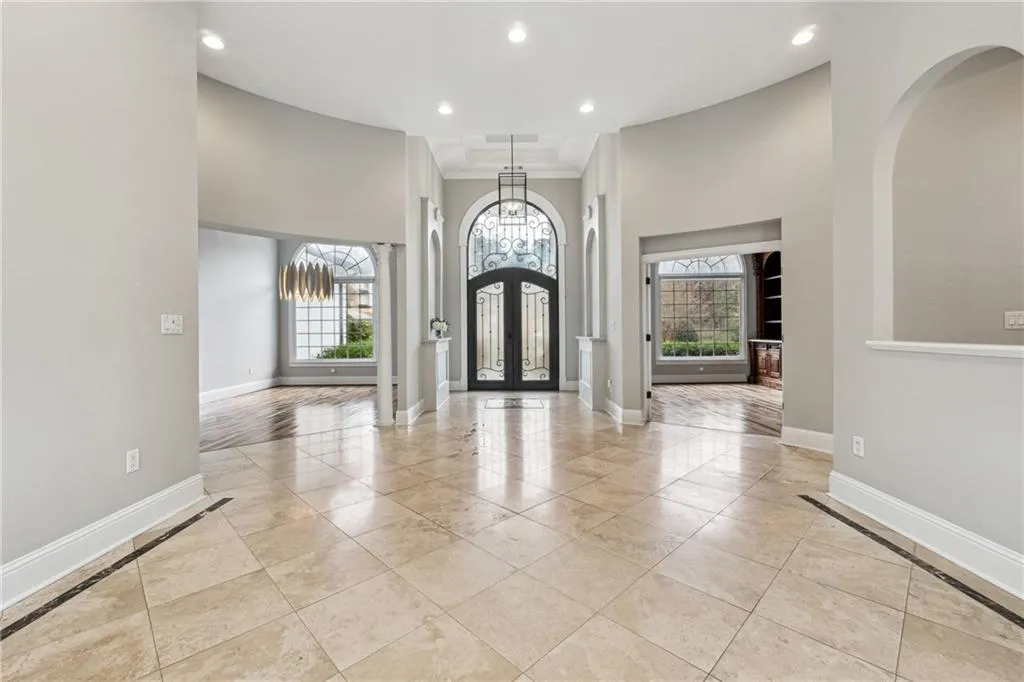 Foyer entrance with ornamental molding, a notable chandelier, and french doors