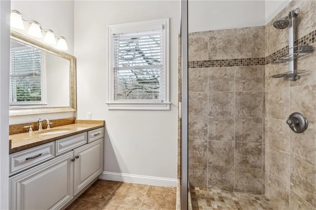 Bathroom featuring vanity, tile patterned floors, and tiled shower