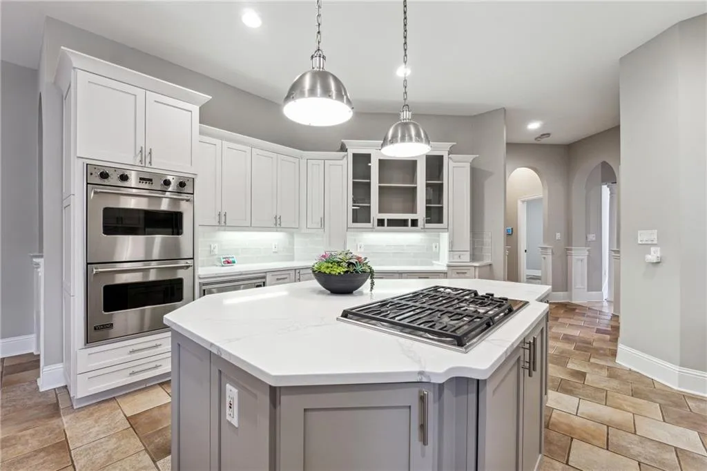 Kitchen with white cabinetry, hanging light fixtures, a kitchen island, stainless steel appliances, and backsplash