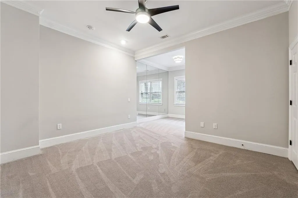 Unfurnished room featuring crown molding, carpet floors, and ceiling fan