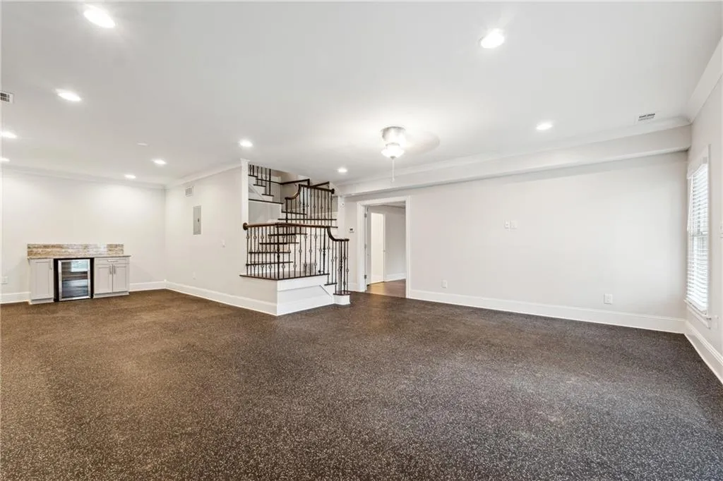 Unfurnished living room featuring crown molding, beverage cooler, and bar area