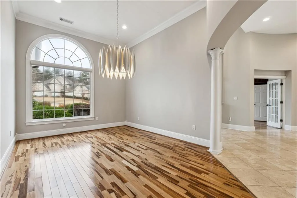 Unfurnished dining area with crown molding, light wood-type flooring, and ornate columns