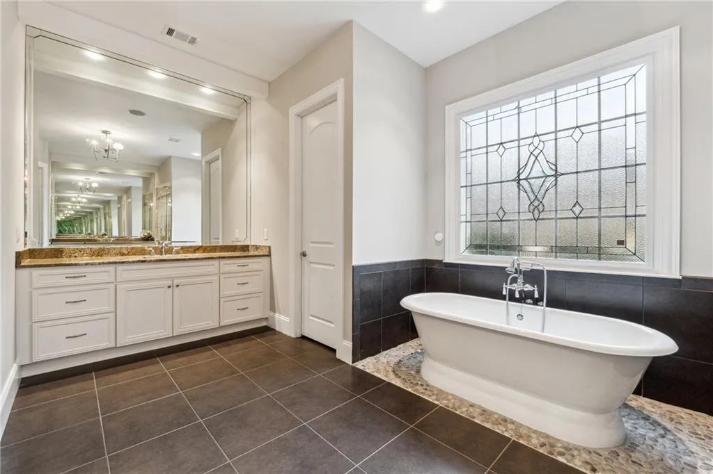 Bathroom with vanity, a tub, tile walls, and tile patterned floors