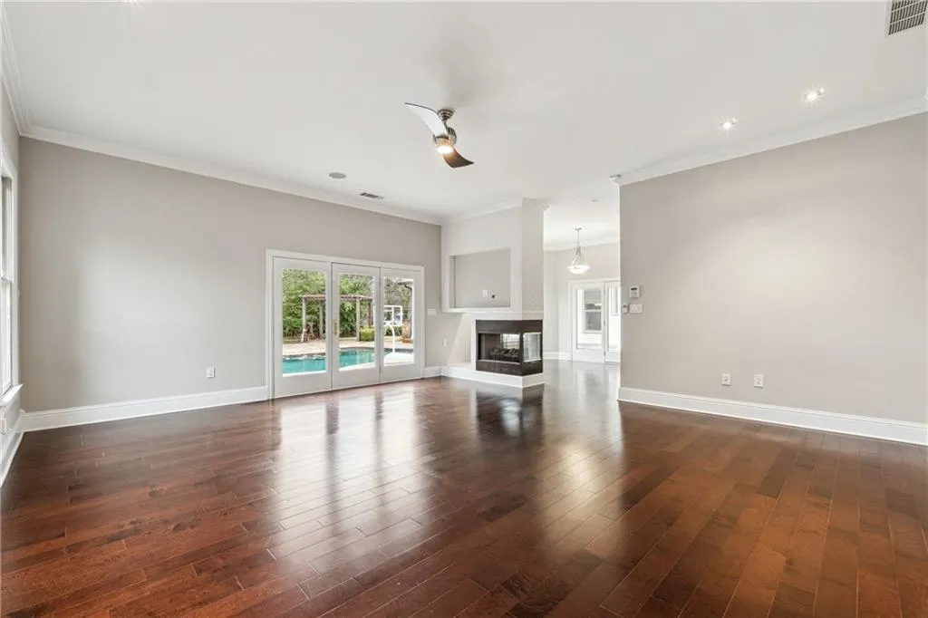 Unfurnished living room featuring ornamental molding, dark hardwood / wood-style floors, and a multi sided fireplace