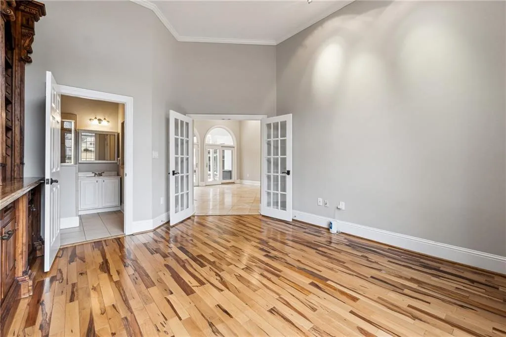 Unfurnished room with light hardwood / wood-style flooring, ornamental molding, french doors, and a high ceiling