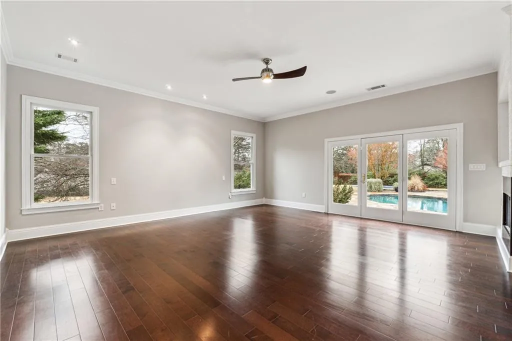 Empty room with crown molding, dark wood-type flooring, and ceiling fan
