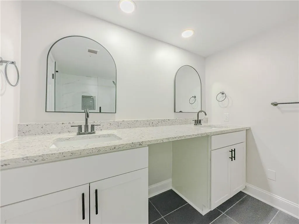 Bathroom with double vanity, tile patterned floors, visible vents, and a sink