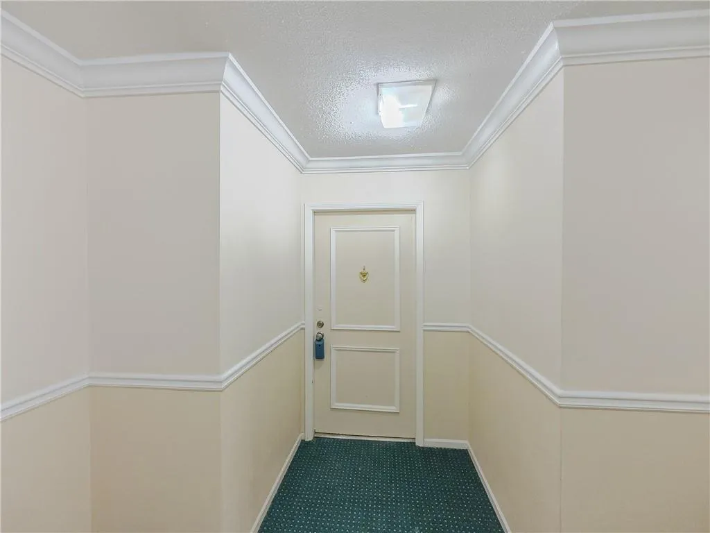 Entryway featuring a textured ceiling, ornamental molding, and carpet
