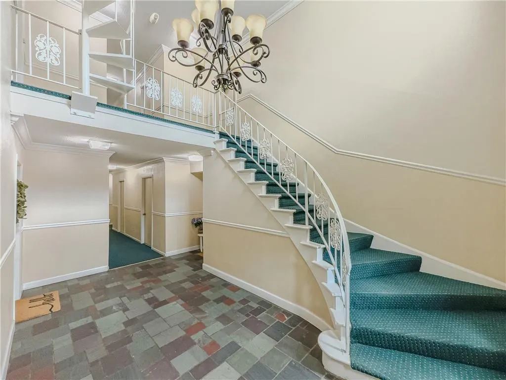 Stairway featuring crown molding, a towering ceiling, a notable chandelier, and baseboards