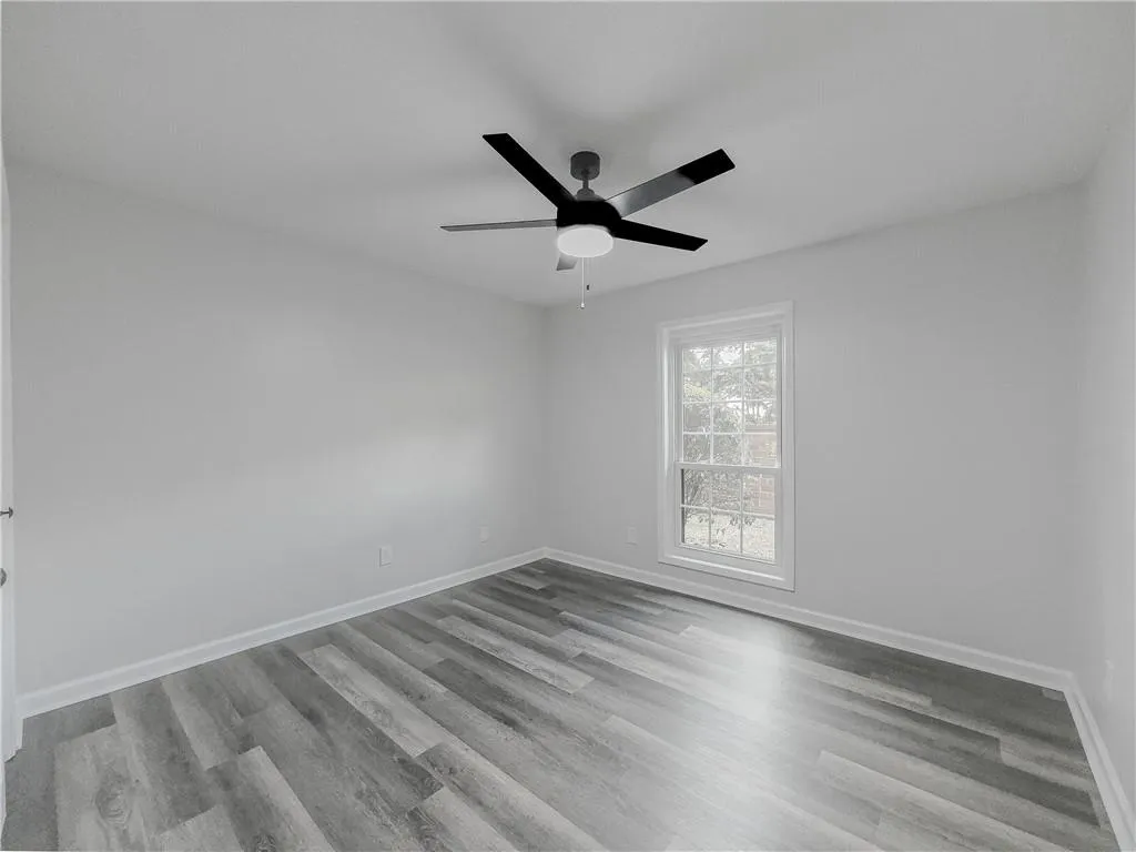 Empty room featuring ceiling fan, baseboards, and wood finished floors