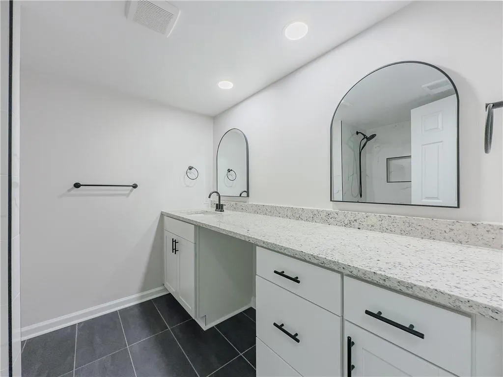 Bathroom featuring a shower, vanity, visible vents, tile patterned floors, and baseboards