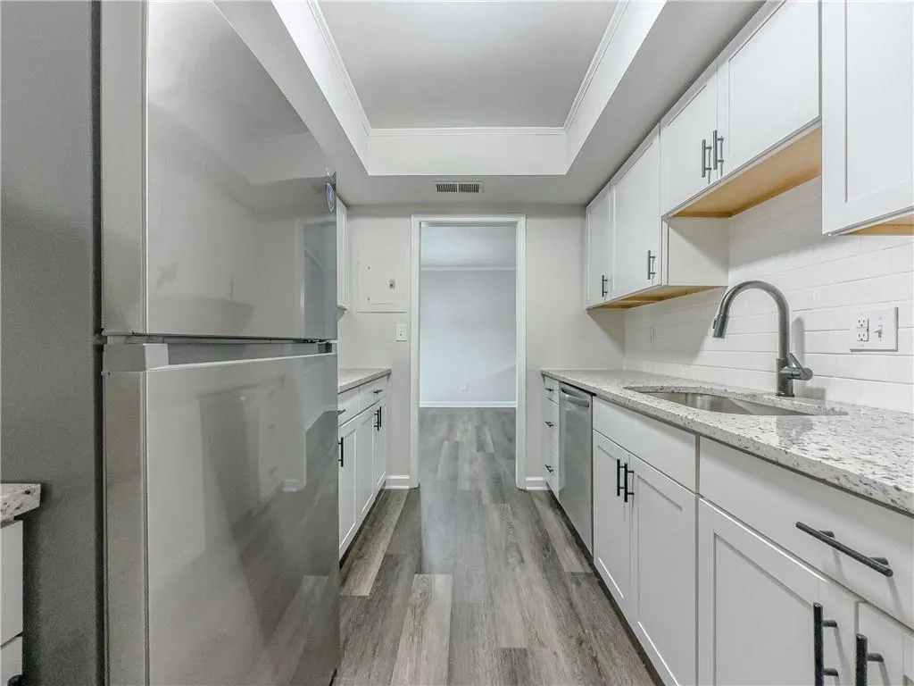 Kitchen with a sink, tasteful backsplash, visible vents, white cabinets, and appliances with stainless steel finishes