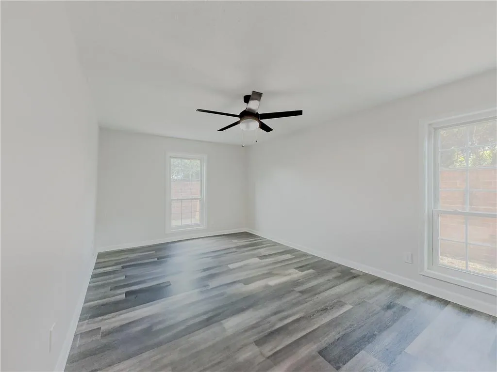 Spare room with a ceiling fan, baseboards, and wood finished floors