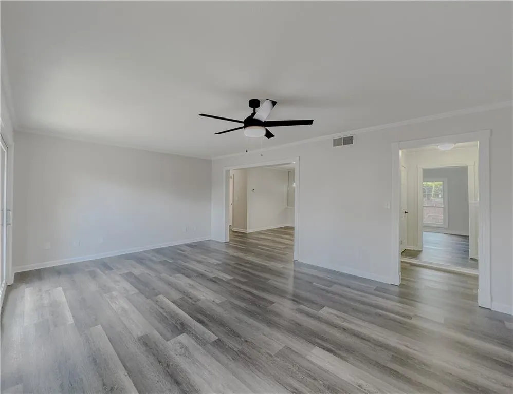 Spare room with ornamental molding, visible vents, and wood finished floors
