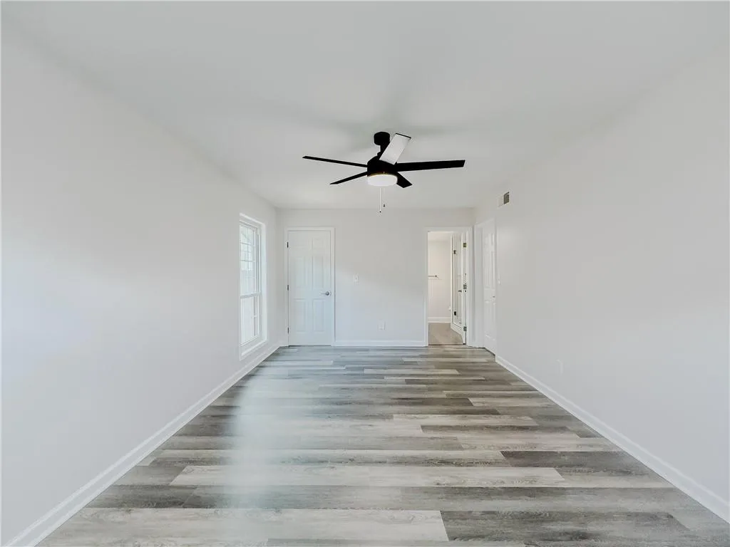 Empty room featuring baseboards, a ceiling fan, visible vents, and wood finished floors