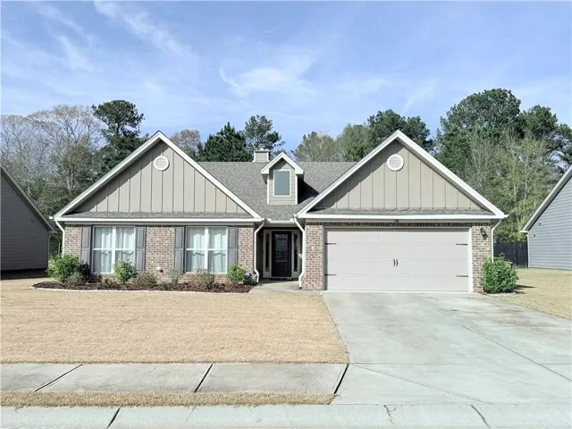 Craftsman-style home featuring board and batten siding, brick siding, concrete driveway, and a chimney
