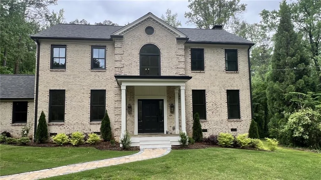 View of front of house featuring brick siding, crawl space, a front lawn, and roof with shingles