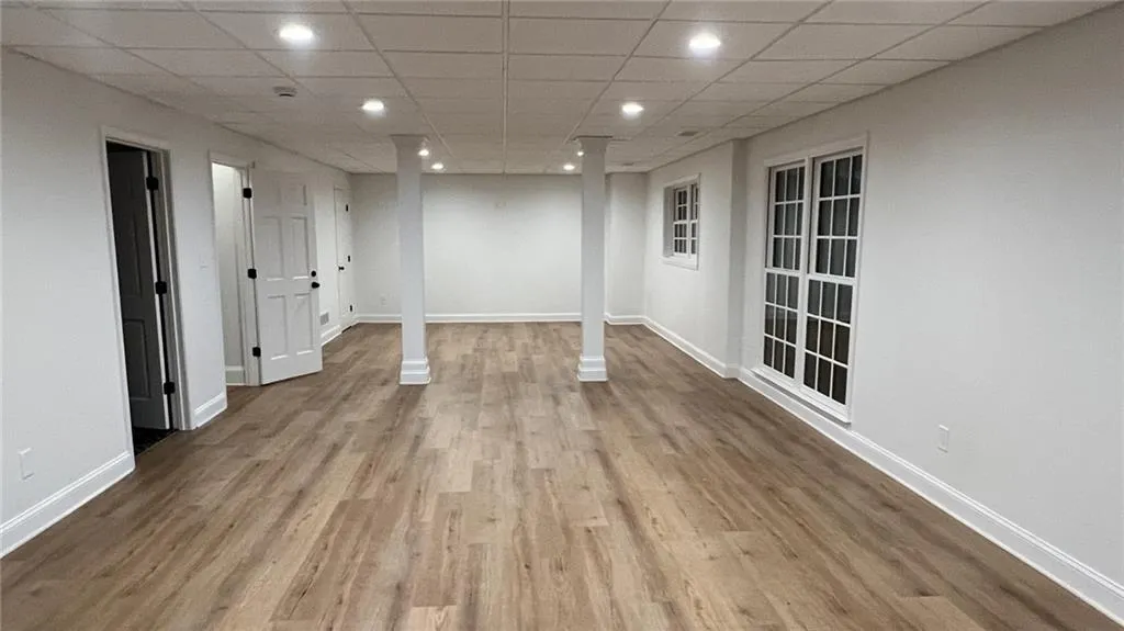 Finished basement with recessed lighting, a drop ceiling, and wood finished floors