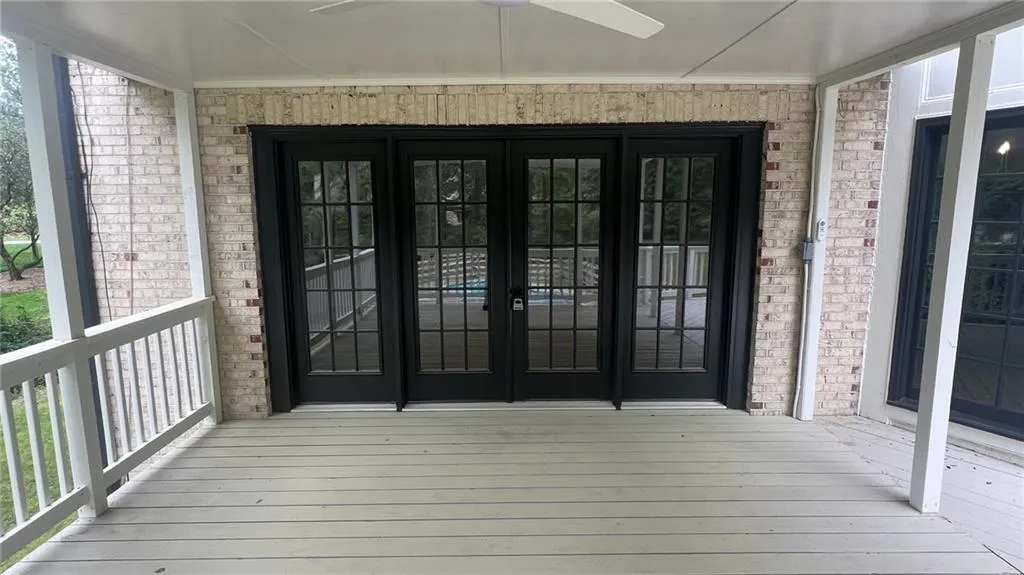 Doorway to property with french doors, a ceiling fan, and brick siding
